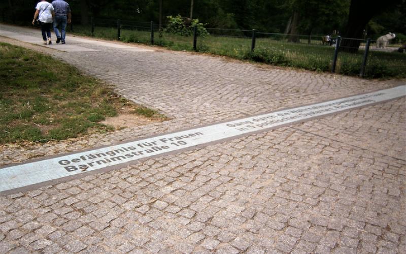 Das Bild zeigt den Hinweis auf das Frauengefängnis Barnimstraße 10 am Überweg vom Friedrichshain zur Weinstraße über die Friedenstraße