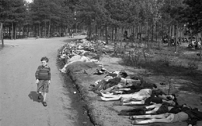 Young Boy Walks Past Corpses, dressed in shorts he walks along a dirt road lined with the corpses of hundreds of prisoners who died at the Bergen-Belsen extermination camp, near the towns of Bergen and Celle, Germany, April 20, 1945.