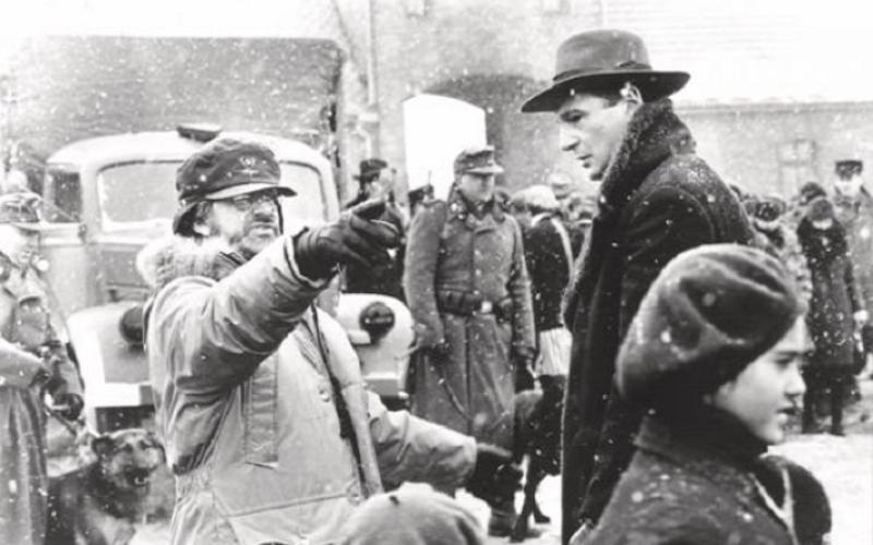 Film Still aus Schindlers Liste das Oskar Schindler in seiner Fabrik zu den jüdischen Arbeiter*innen sprechend zeigt