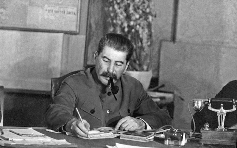 Joseph Stalin sitzt Pfeife rauchend an seinem Schreibtisch