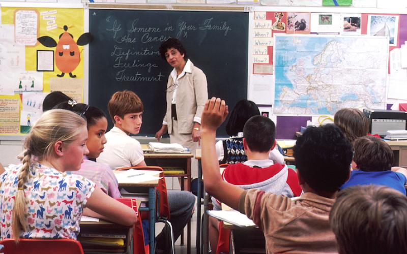 Lehrerin an der Tafel in vollem Klassenzimmer, 1985.