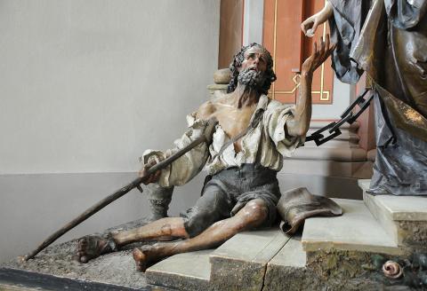 Der Bettler von Ludwig Moroder der Gruppe der Heiligen Elisabeth des Rudolf Moroder in der Pfarrkirche St. Ulrich in Gröden.  © User: Wolfgang Moroder, Beggar Saint Elisabeth Group, 2008. Quelle: Wikimedia Commons (CC BY-SA 3.0)